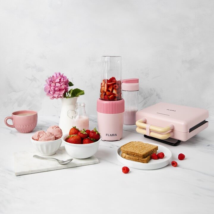 Conjunto de cozinha com uma sanduicheira e uma liquidificadora acompanhado de tostas morangos e gelado com cores vibrantes.