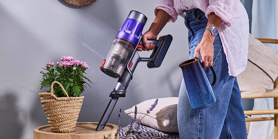 Detalhe do aspirador vertical Flama nas mãos de um homem ao ser utilizado para aspirar a casa, demonstrando praticidade e conforto na sua utilização